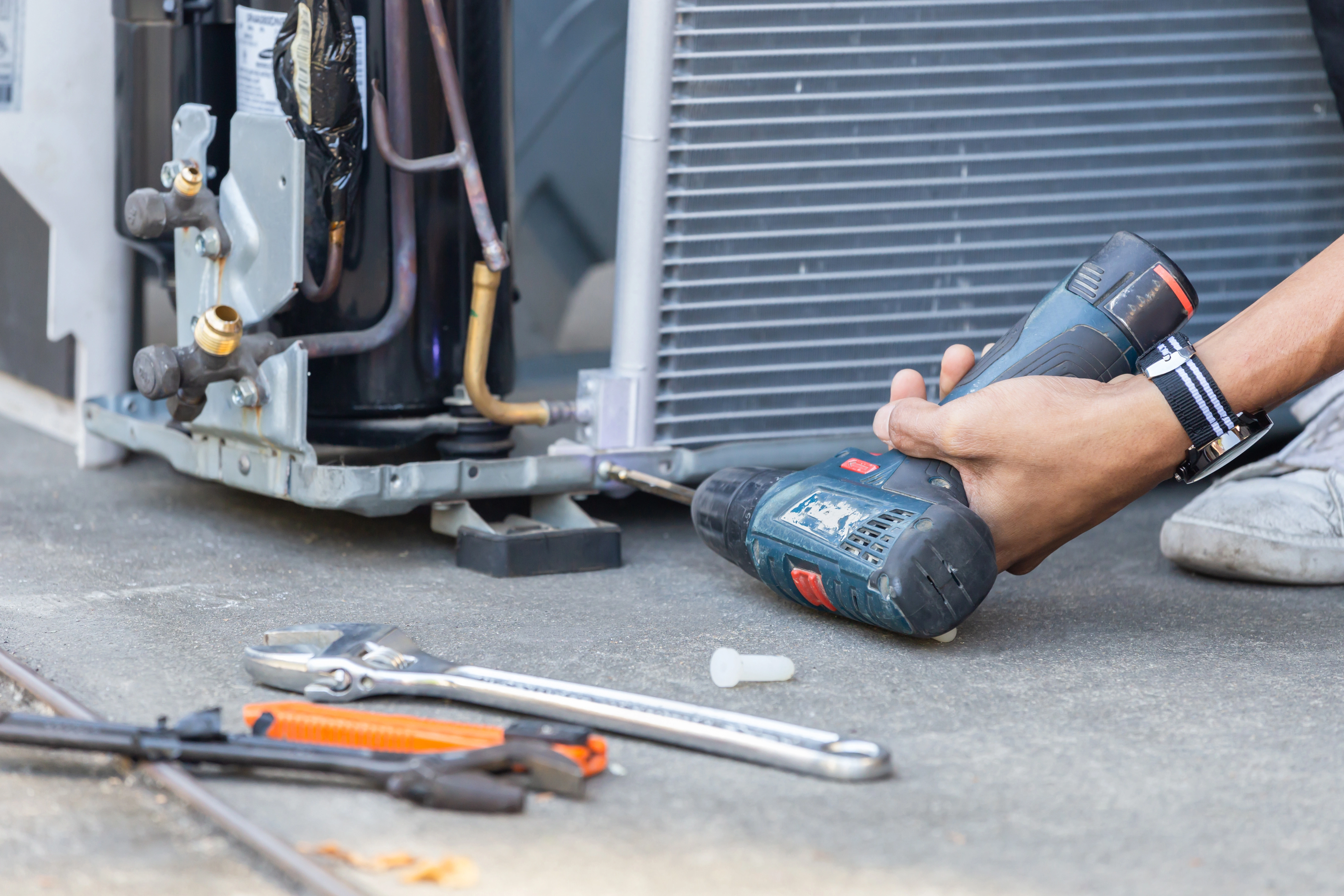 A technician cleans an AC compressor with a power drill as part of an AC tune-up in Tulsa.